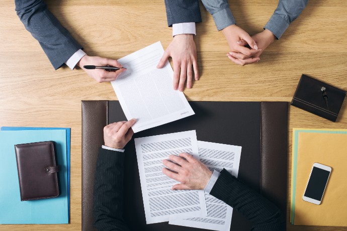 business-man-and-woman-sitting-at-the-lawyers-s-desk-and-signing-important-documents-hands-top-view